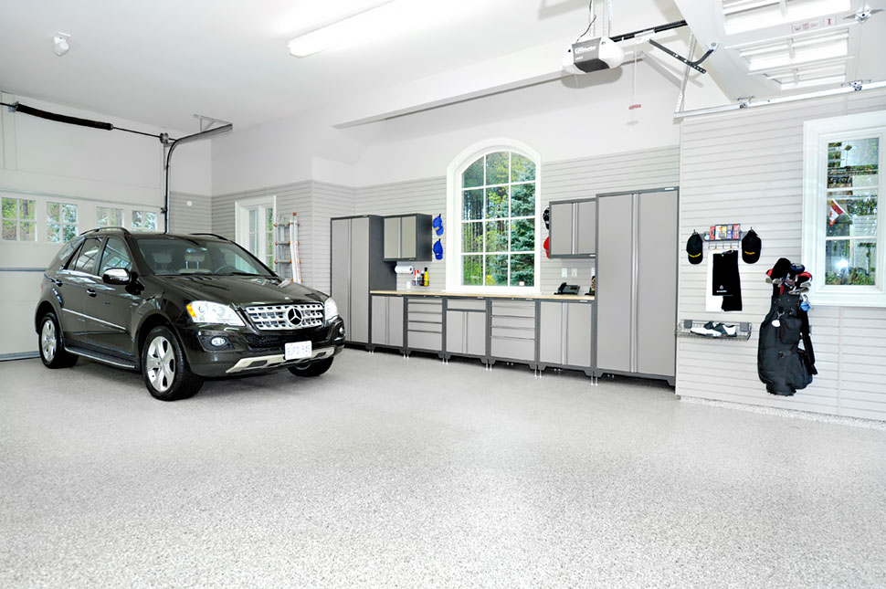 A very large garage with lots of cabinets along the wall and a car parked inside.
